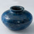 A short and wide wooden vase dyed a deep, marbled blue color. 