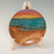 A wooden platter sitting on a stand. The platter has a beach landscape at sunset hand-painted on it. 