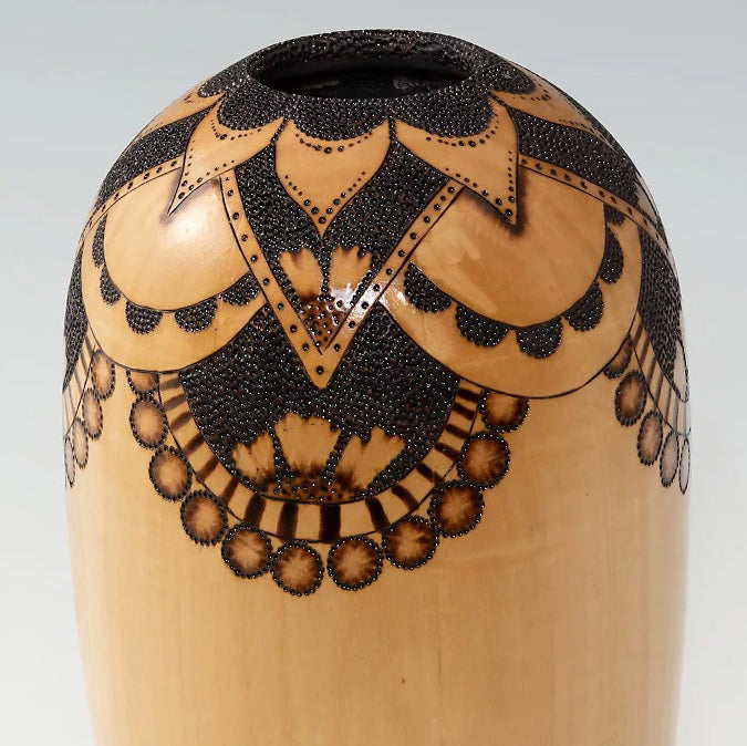 Light colored vase with intricate woodburning details