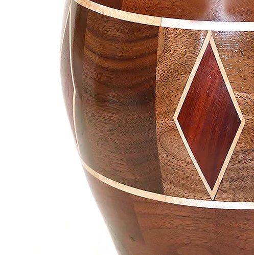 A closeup of a segmented vase with a diamond-inlayed pattern in multiple colors of wood. 