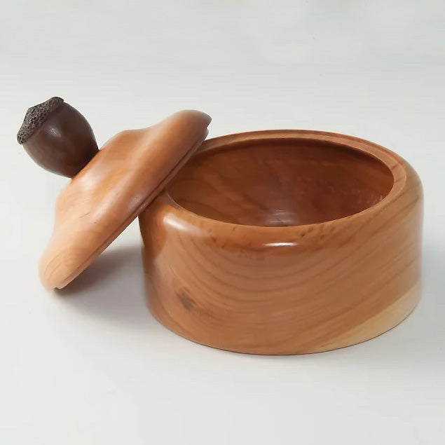 A woodturned, lidded bowl with an acorn handle on top. 