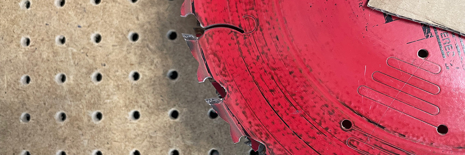 Red saw blade sitting on top of pegboard background 
